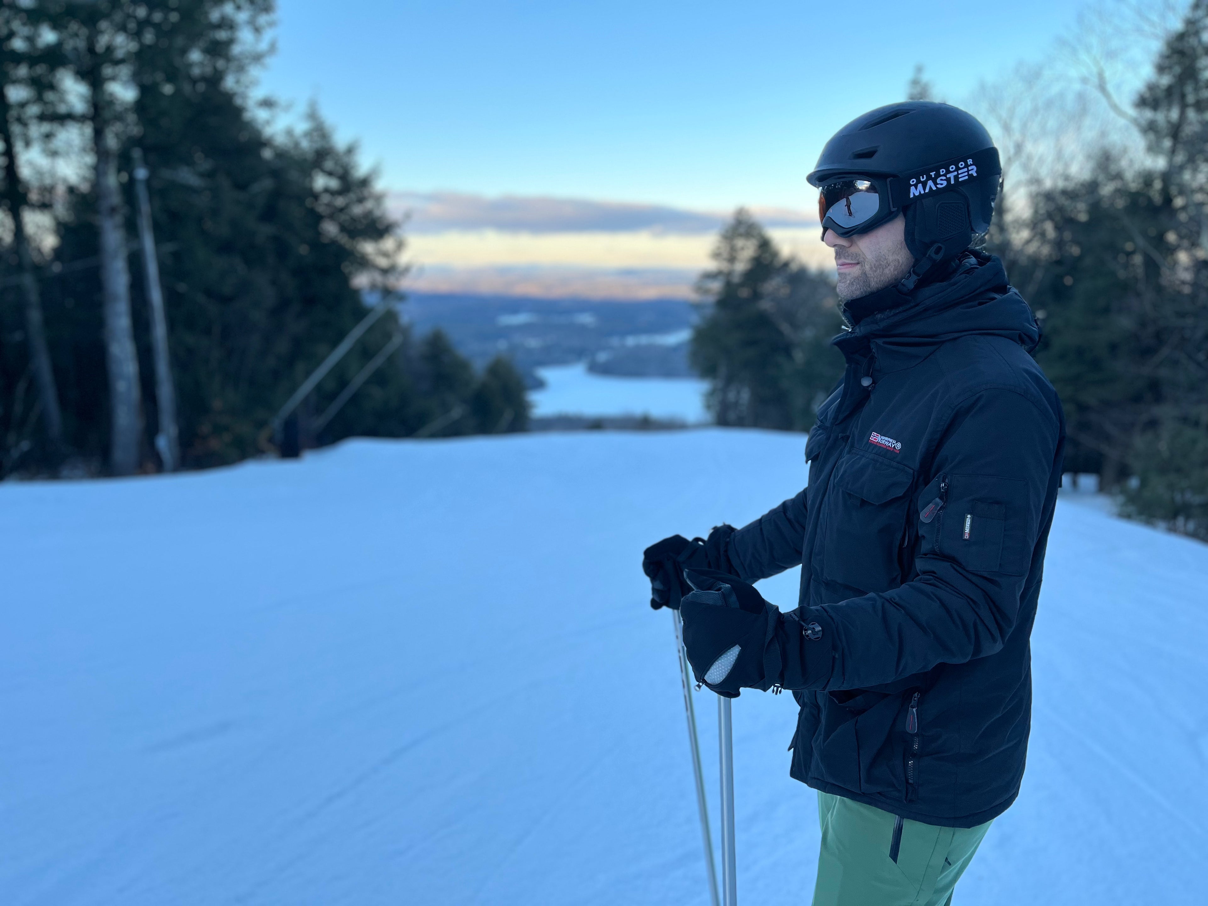 Person skiing on a snowy slope with trees and a clear sky in the background